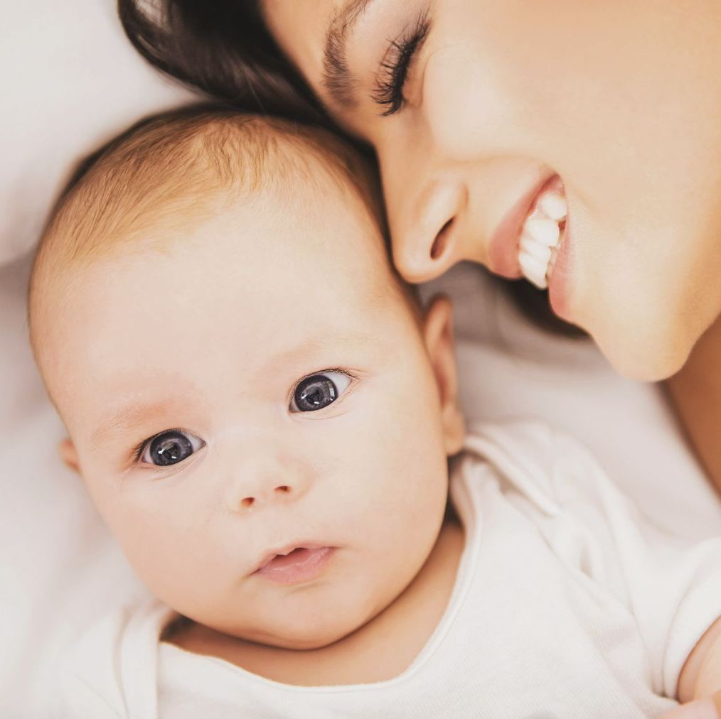 bebe sobre coclha con recorte cara de madre sonriente